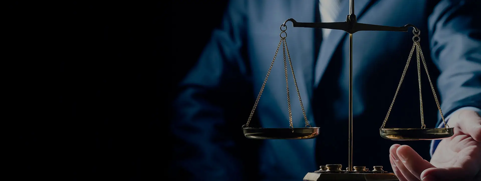 Advogado de terno azul segurando a balança da justiça em bronze, fundo escuro dramático, iluminação de contraste, mood sofisticado e sério, fotografia profissional editorial