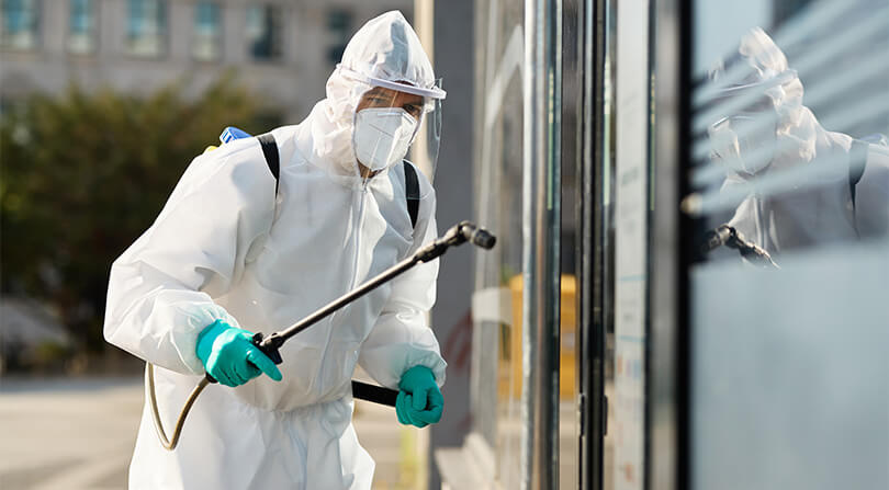 Imagem de uma pessoa usando EPI aplicando produto químico em uma parede de vidro ilustrando direito do trabalho insalubridade.