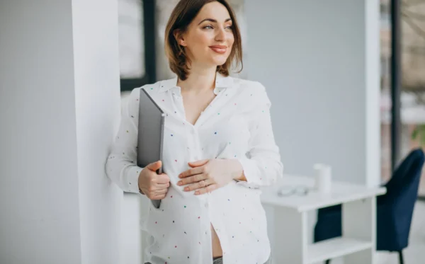 Uma jovem mulher está grávida e continua a trabalhar em um escritório.