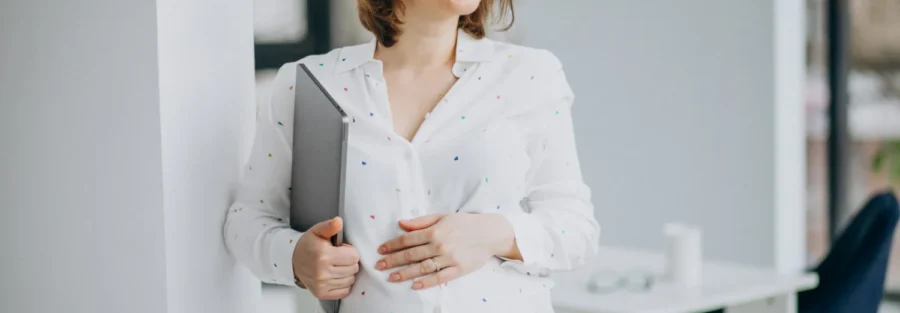 Uma jovem mulher está grávida e continua a trabalhar em um escritório.