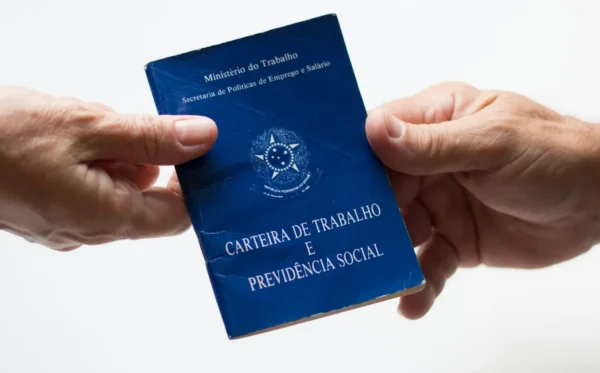 Imagem de duas pessoas segurando uma carteira de trabalho, simbolizando quem tem direito ao seguro desemprego.