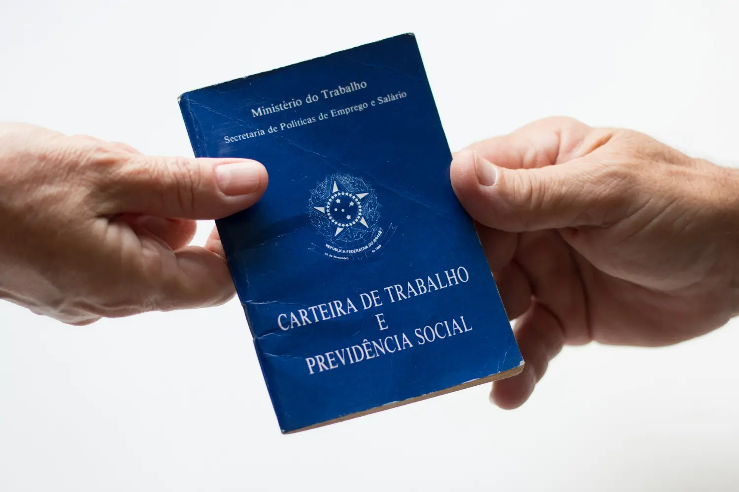 Imagem de duas pessoas segurando uma carteira de trabalho, simbolizando quem tem direito ao seguro desemprego.